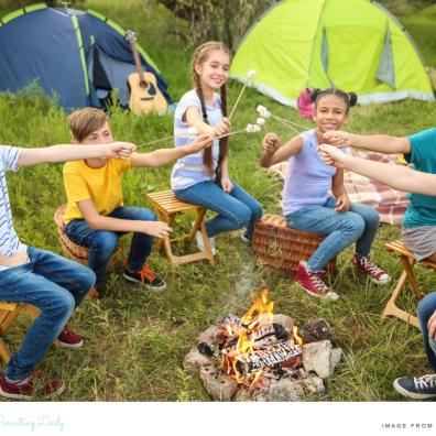 picture of children sat round a camp fire toasting marshmallows at a summer camp