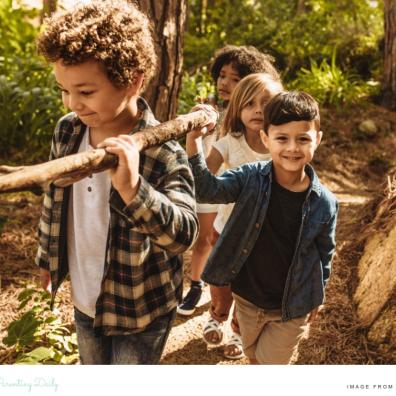 picture of happy children carrying a branch whilst at a nature childrens camp