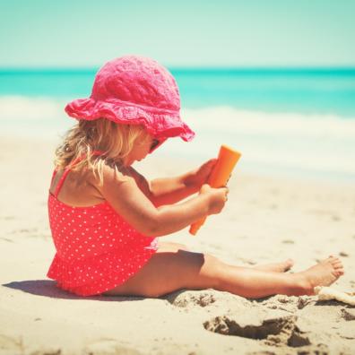 picture of child on a beach putting suncream on