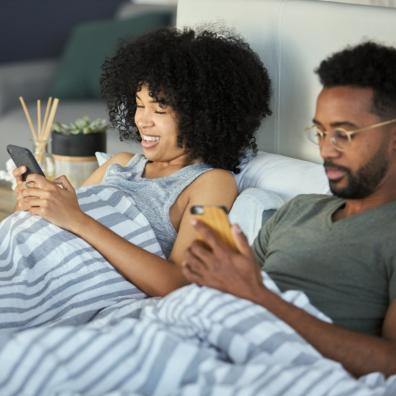 picture of a couple doing a quiz on their phones in bed