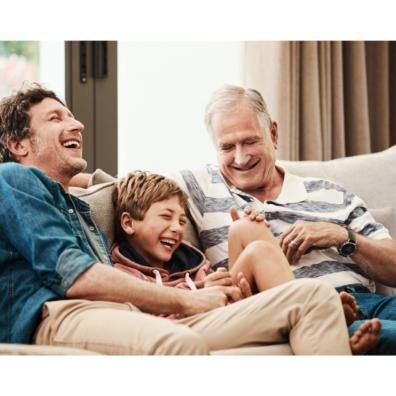 Three generations of boys laughing together on a sofa