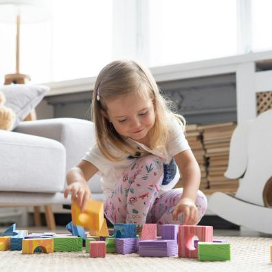 Little cute girl playing block toys in playroom at home