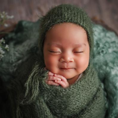 picture of a happy baby wrapped in a green blanket