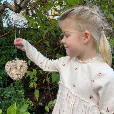 picture of girl holding a home made bird feeder in the garden