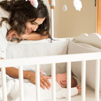 picture of a mum putting a baby to sleep in a neutral cot