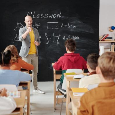 picture of an older, male teacher teaching a classroom of students
