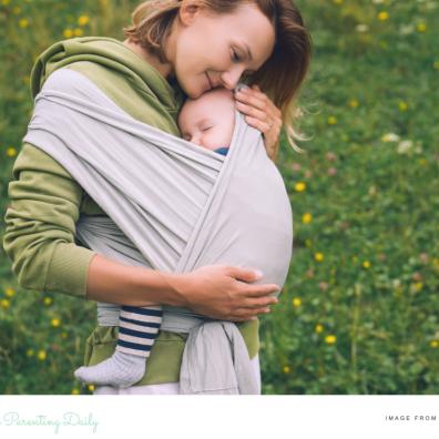 picture of a woman with a baby sleeping in a sling outdoors in nature