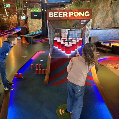 picture of children playing on the beer pong course at Puttshack london indoor crazy golf